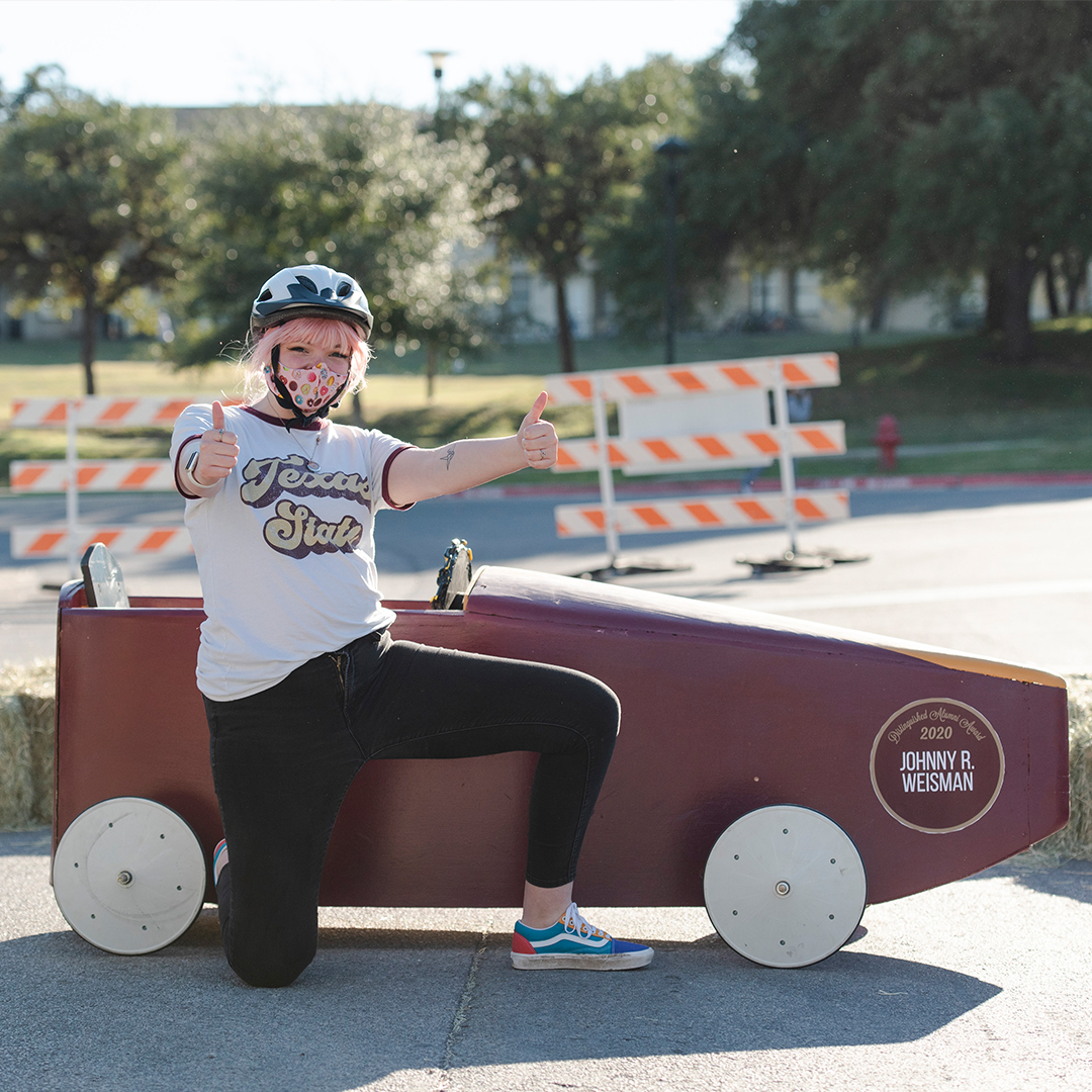 student posing with soapbox derby car